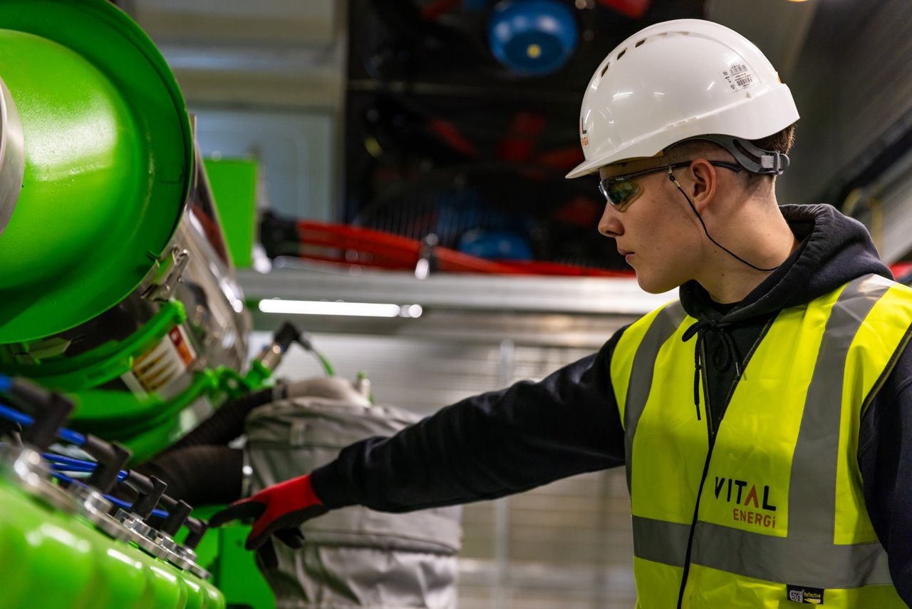 Safety-focused worker operating machinery indoors, wearing protective gear.
